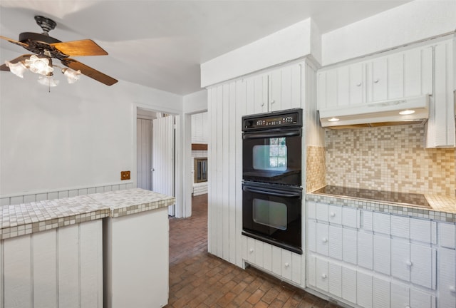 kitchen with tasteful backsplash, tile countertops, white cabinets, ceiling fan, and black appliances