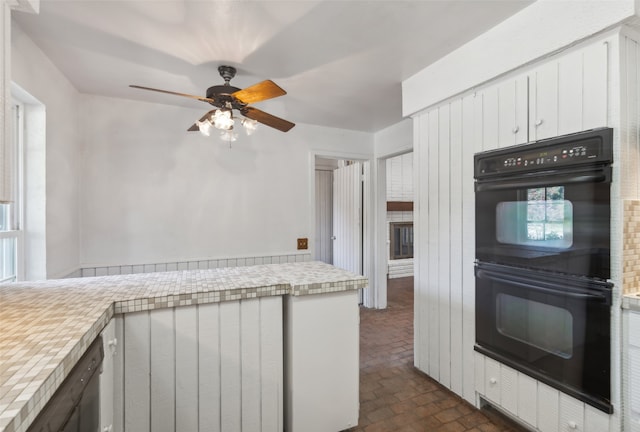 kitchen with ceiling fan, black double oven, and white cabinets