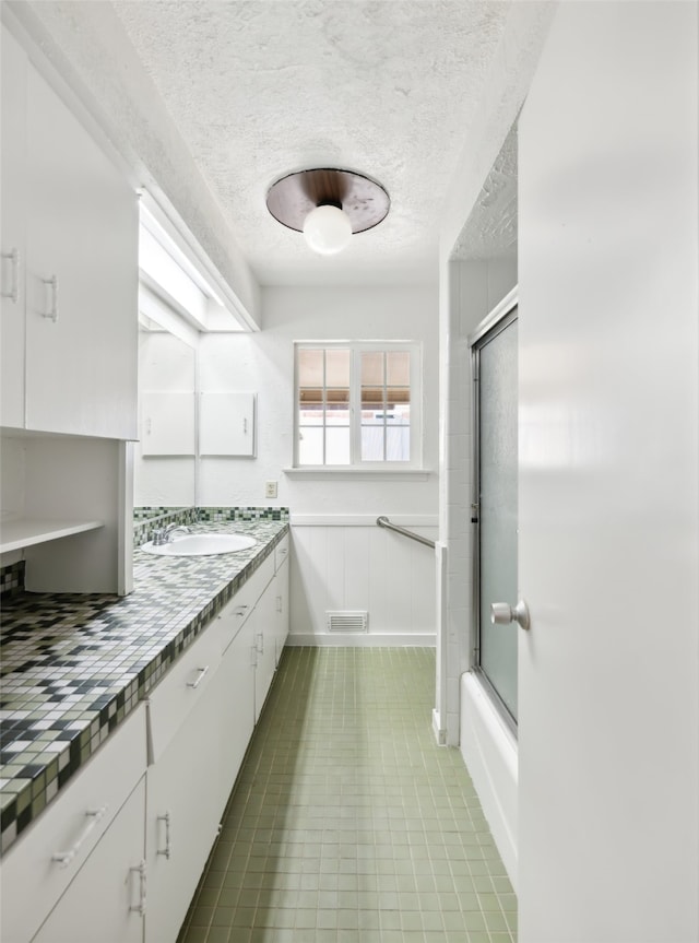 bathroom featuring vanity, tile patterned floors, a textured ceiling, and shower / bath combination with glass door