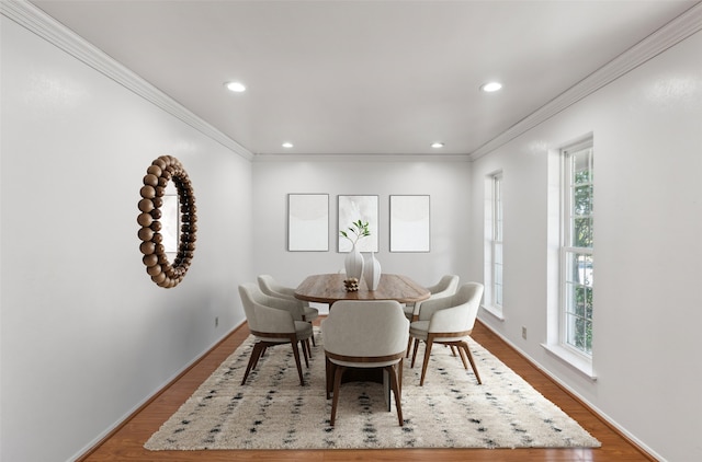 dining room featuring wood-type flooring, crown molding, and a healthy amount of sunlight