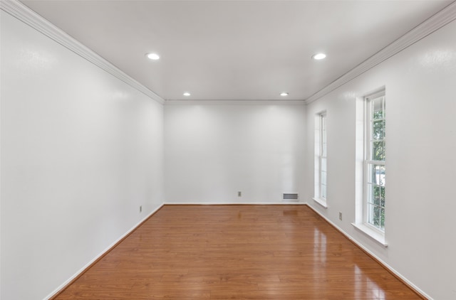 empty room with a healthy amount of sunlight, wood-type flooring, and ornamental molding