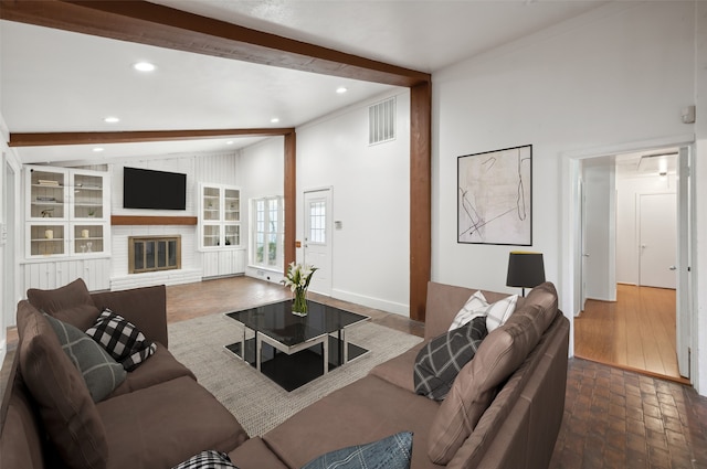 living room with a brick fireplace and lofted ceiling with beams