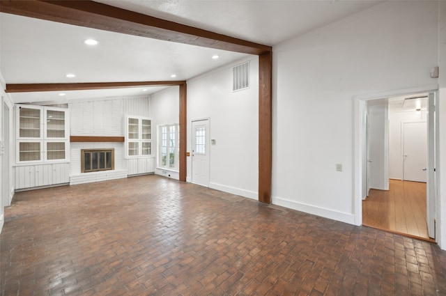 unfurnished living room featuring a brick fireplace and lofted ceiling with beams