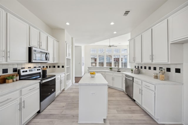 kitchen with sink, white cabinetry, a kitchen island, stainless steel appliances, and backsplash