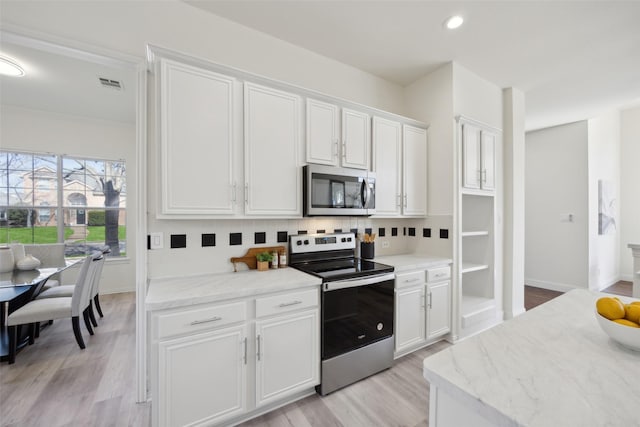 kitchen featuring tasteful backsplash, white cabinets, light hardwood / wood-style floors, stainless steel appliances, and light stone countertops