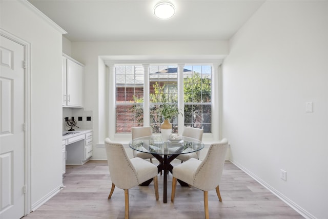 dining space featuring crown molding and light hardwood / wood-style flooring