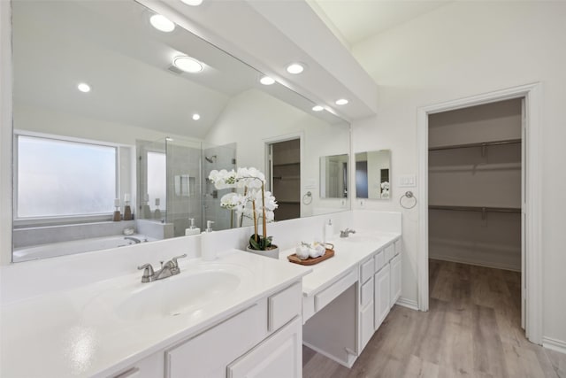 bathroom featuring walk in shower, wood-type flooring, vaulted ceiling, and vanity