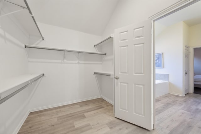 spacious closet with light hardwood / wood-style flooring and vaulted ceiling