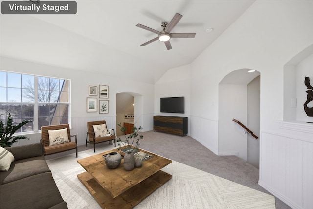 carpeted living room with ceiling fan and vaulted ceiling