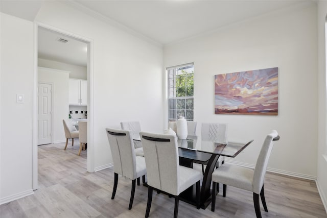 dining space featuring crown molding and light wood-type flooring