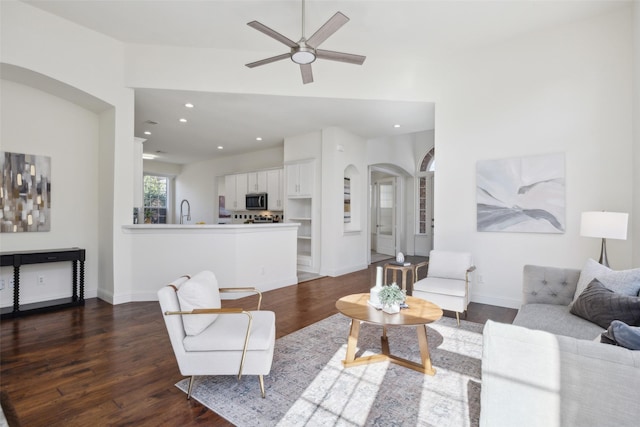 living room featuring ceiling fan, sink, and dark hardwood / wood-style flooring