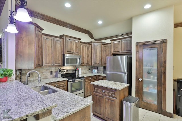 kitchen with decorative light fixtures, decorative backsplash, sink, stainless steel appliances, and light stone counters