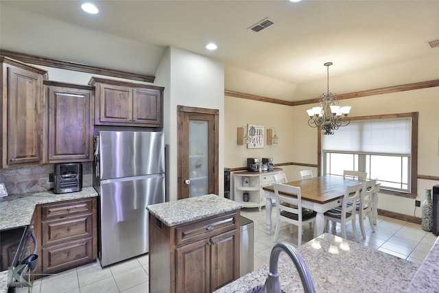 kitchen featuring stainless steel fridge, light tile patterned flooring, light stone counters, and pendant lighting