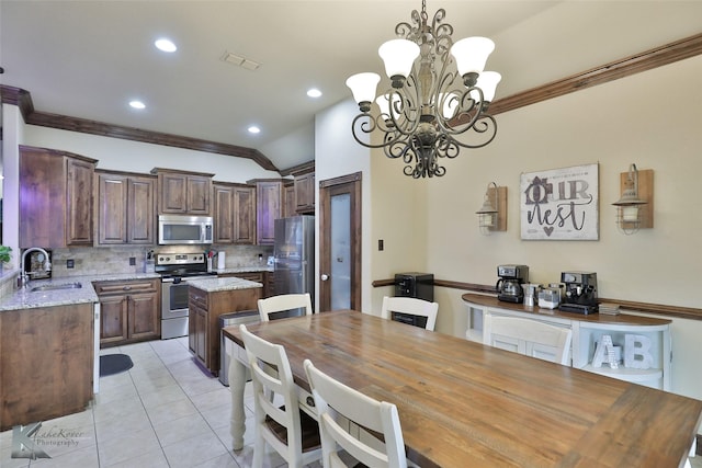 dining area featuring an inviting chandelier, light tile patterned flooring, lofted ceiling, ornamental molding, and sink