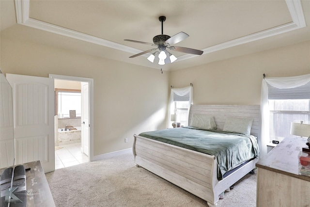 bedroom with ceiling fan, light colored carpet, a raised ceiling, and ensuite bath