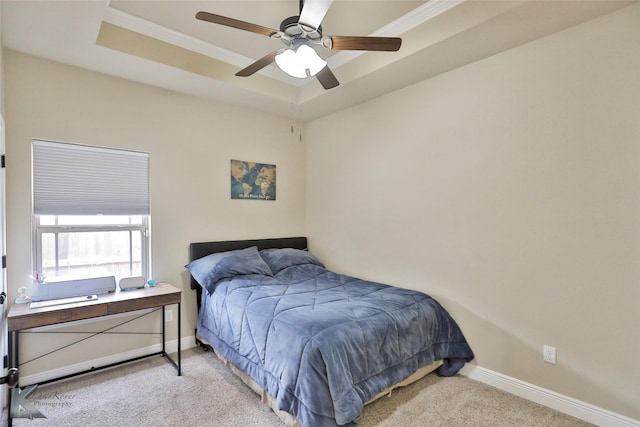 bedroom with ceiling fan, light colored carpet, crown molding, and a tray ceiling