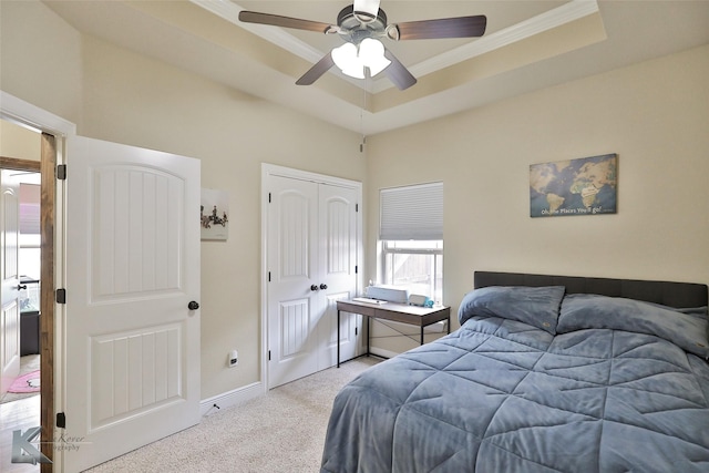 carpeted bedroom featuring ceiling fan, a closet, and a tray ceiling