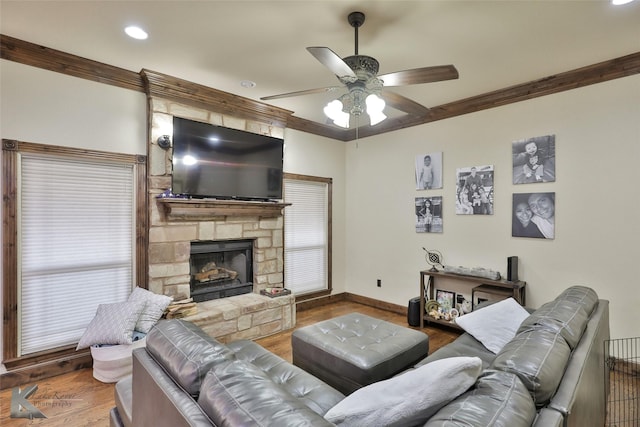 living room with ceiling fan, wood-type flooring, a fireplace, and crown molding