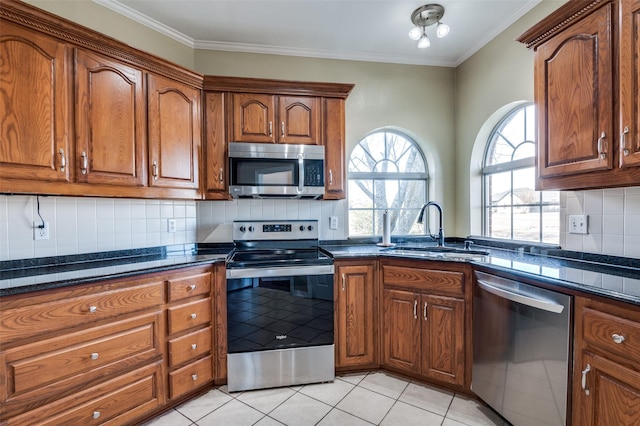 kitchen featuring light tile patterned floors, sink, appliances with stainless steel finishes, and crown molding