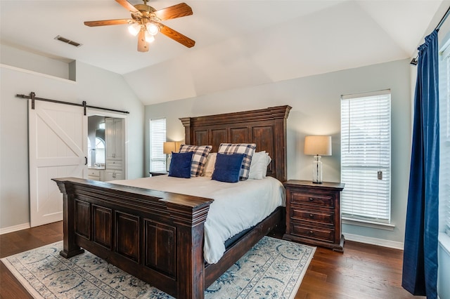 bedroom featuring ceiling fan, a barn door, dark hardwood / wood-style floors, and multiple windows