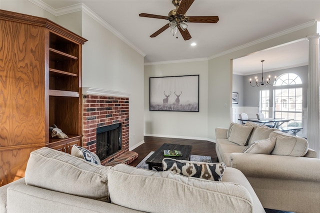 living room featuring a brick fireplace, dark wood-type flooring, crown molding, and ceiling fan with notable chandelier