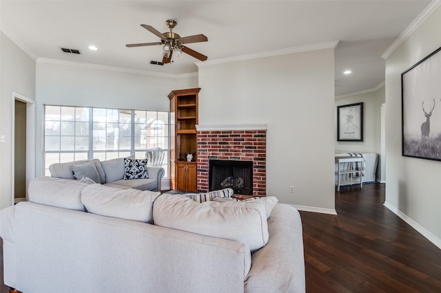 living room with a brick fireplace, crown molding, dark hardwood / wood-style floors, and ceiling fan