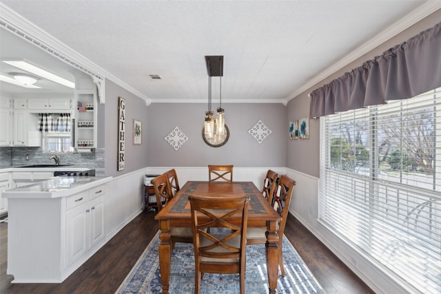 dining room with sink, dark hardwood / wood-style floors, and crown molding