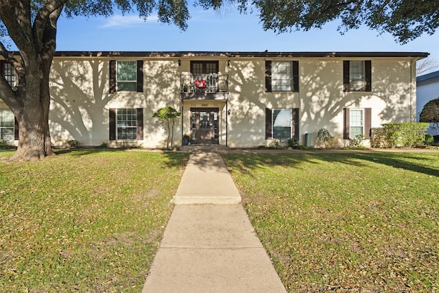 view of front of house with a balcony and a front lawn