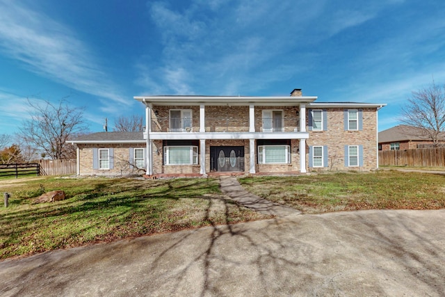 view of front of house featuring a balcony and a front yard