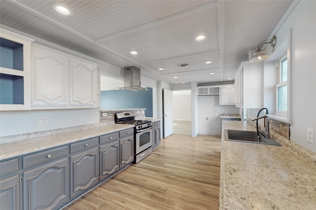 kitchen with white cabinetry, light hardwood / wood-style floors, island exhaust hood, gas stove, and sink