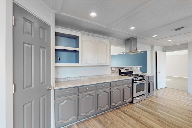 kitchen featuring island exhaust hood, stainless steel range with gas stovetop, gray cabinets, and light hardwood / wood-style flooring