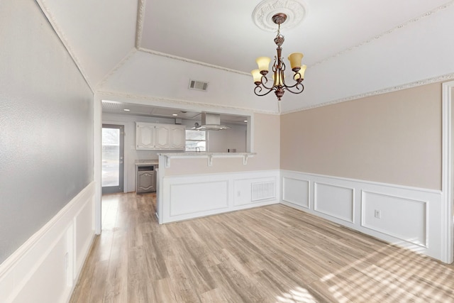 unfurnished dining area with light hardwood / wood-style floors, ornamental molding, and a chandelier