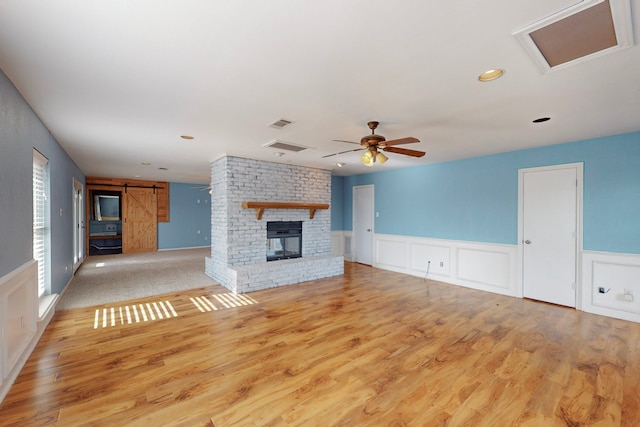 unfurnished living room with ceiling fan, a brick fireplace, and light hardwood / wood-style flooring