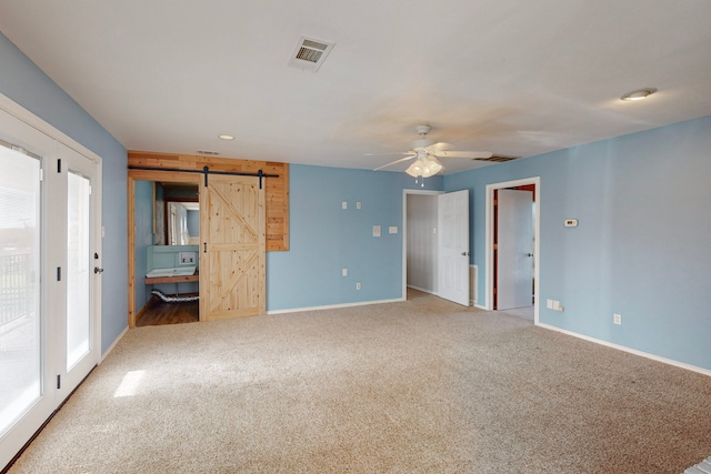 interior space featuring carpet, a barn door, and ceiling fan