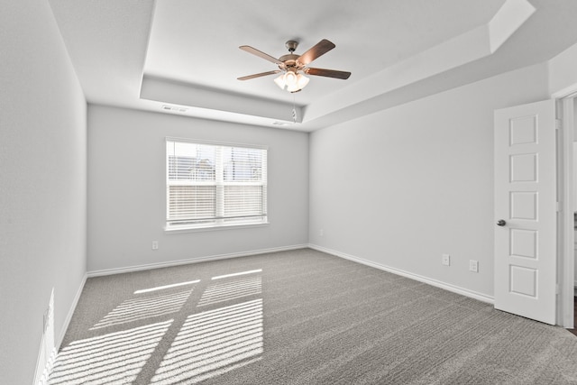 carpeted spare room featuring ceiling fan and a raised ceiling