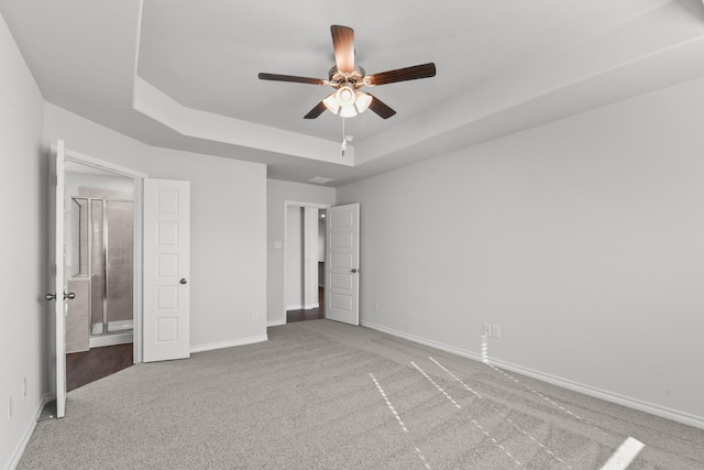 unfurnished bedroom featuring a raised ceiling, ceiling fan, and carpet