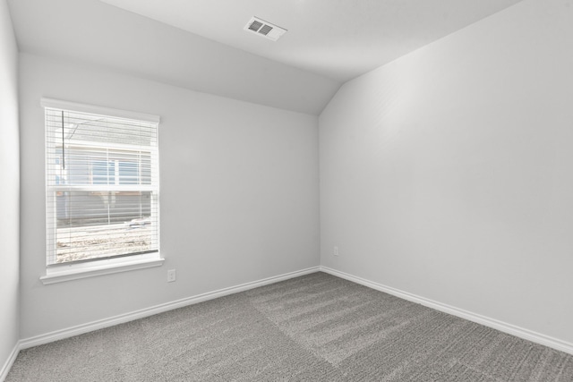 carpeted empty room with vaulted ceiling