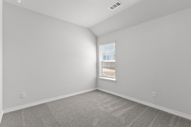 carpeted spare room with vaulted ceiling