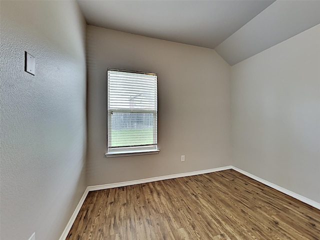 spare room featuring lofted ceiling and wood-type flooring