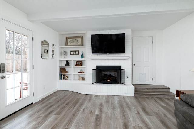 living room with light hardwood / wood-style flooring, beam ceiling, and a fireplace