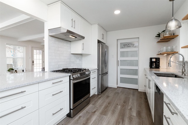 kitchen with light stone countertops, stainless steel appliances, white cabinetry, and sink