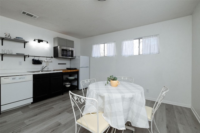 dining room with sink, a textured ceiling, and light wood-type flooring