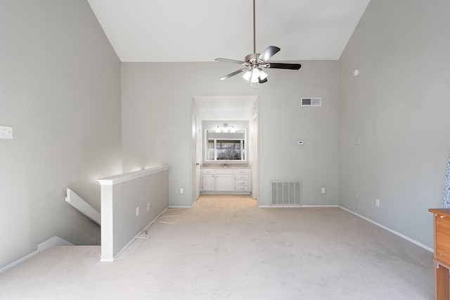 unfurnished living room with ceiling fan, light colored carpet, and lofted ceiling