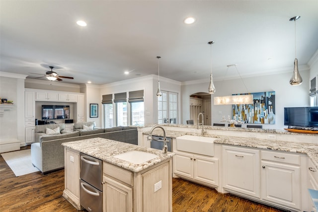 kitchen with pendant lighting, sink, a kitchen island with sink, dark wood-type flooring, and light stone counters