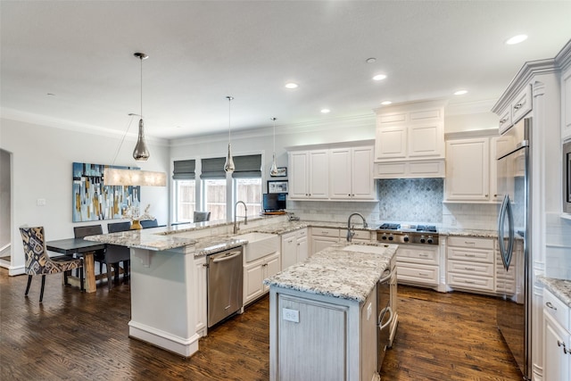 kitchen featuring light stone countertops, hanging light fixtures, a large island, and sink