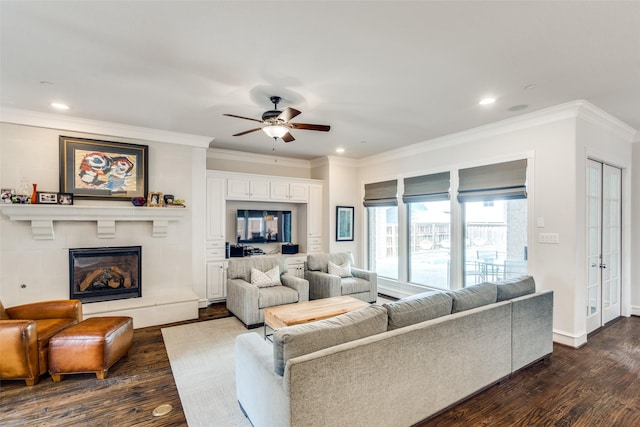 living room featuring ceiling fan, dark hardwood / wood-style floors, crown molding, and a fireplace