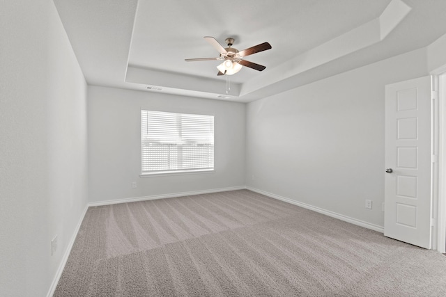 carpeted empty room featuring ceiling fan and a tray ceiling