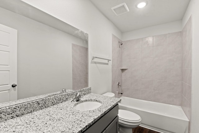 full bathroom featuring toilet, tiled shower / bath, hardwood / wood-style floors, and vanity