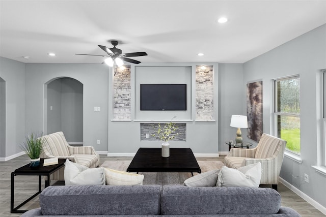 living area with recessed lighting, arched walkways, a ceiling fan, and light wood-type flooring