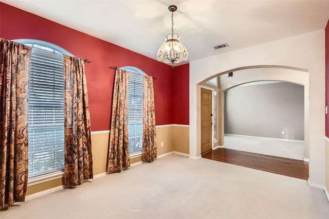 spare room with carpet floors and a chandelier